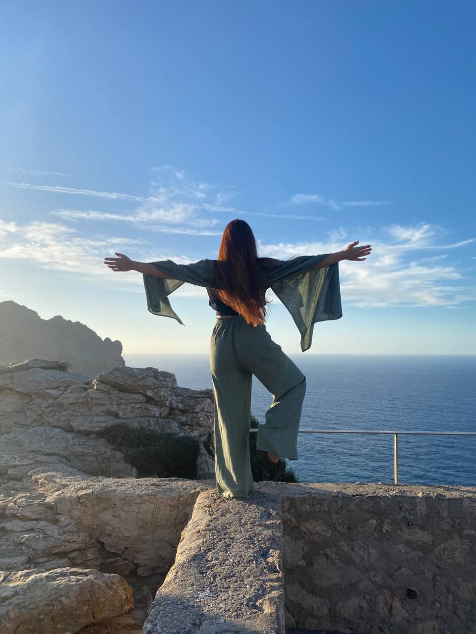 Lara steht mit ausgebreiteten Armen am Meer