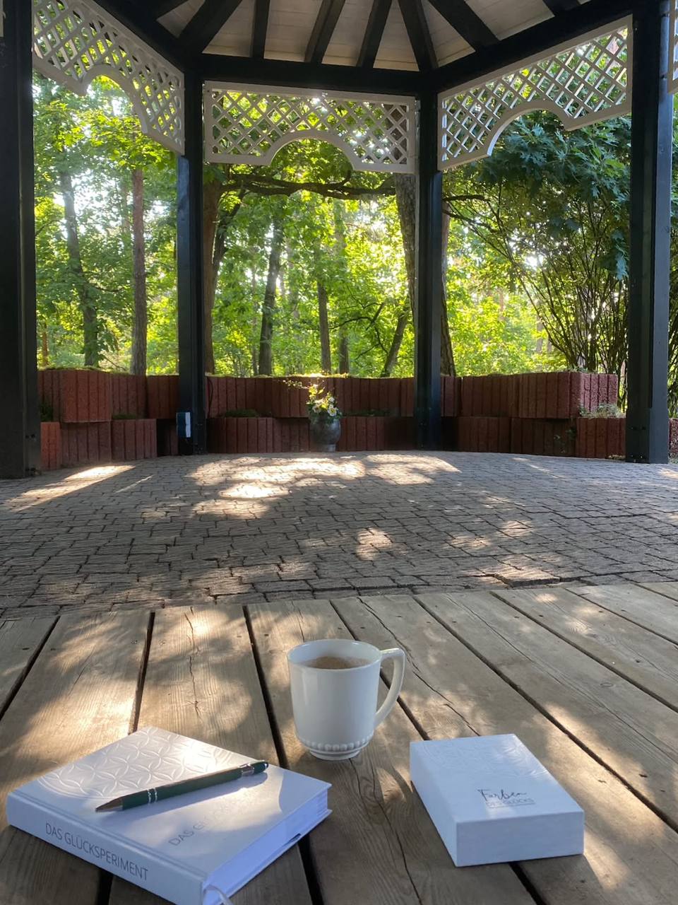 Notizbuch, Stift und Tasse auf einem Holztisch im Pavillon am Waldrand