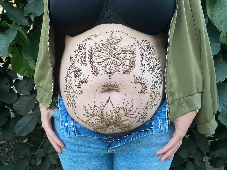 Schwangerschaftsbauch mit großflächigem Henna-Ornament aus Schmetterling und Lotus