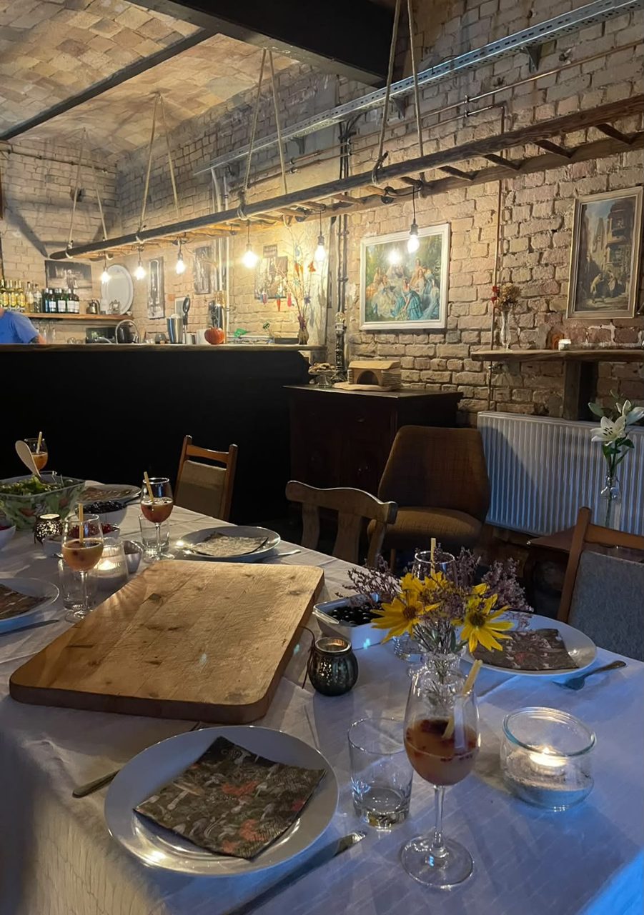 Gedeckter Tisch mit Blumen und Kerzen in einem Raum mit Backsteinwand