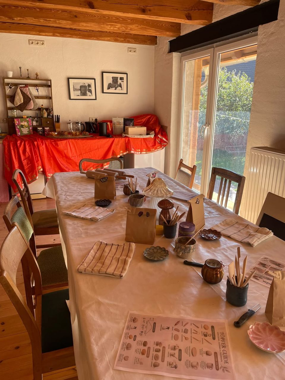 Gedeckter Holztisch mit Stiften, Notizen und Keramik in einem hellen Raum