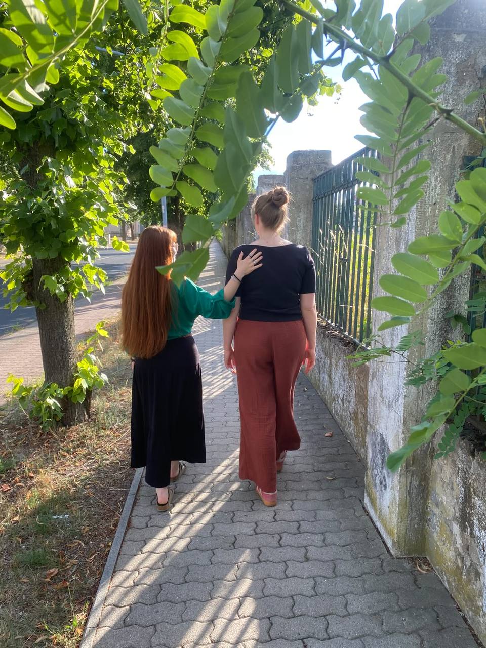 Zwei Frauen gehen nebeneinander einen sonnigen Weg entlang